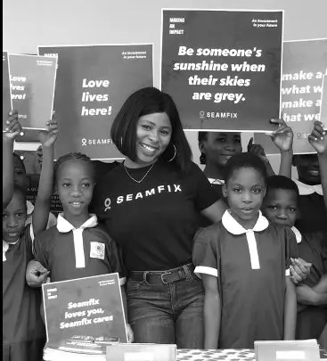 A Seamfix team member with schoolchildren holding handwritten signs
